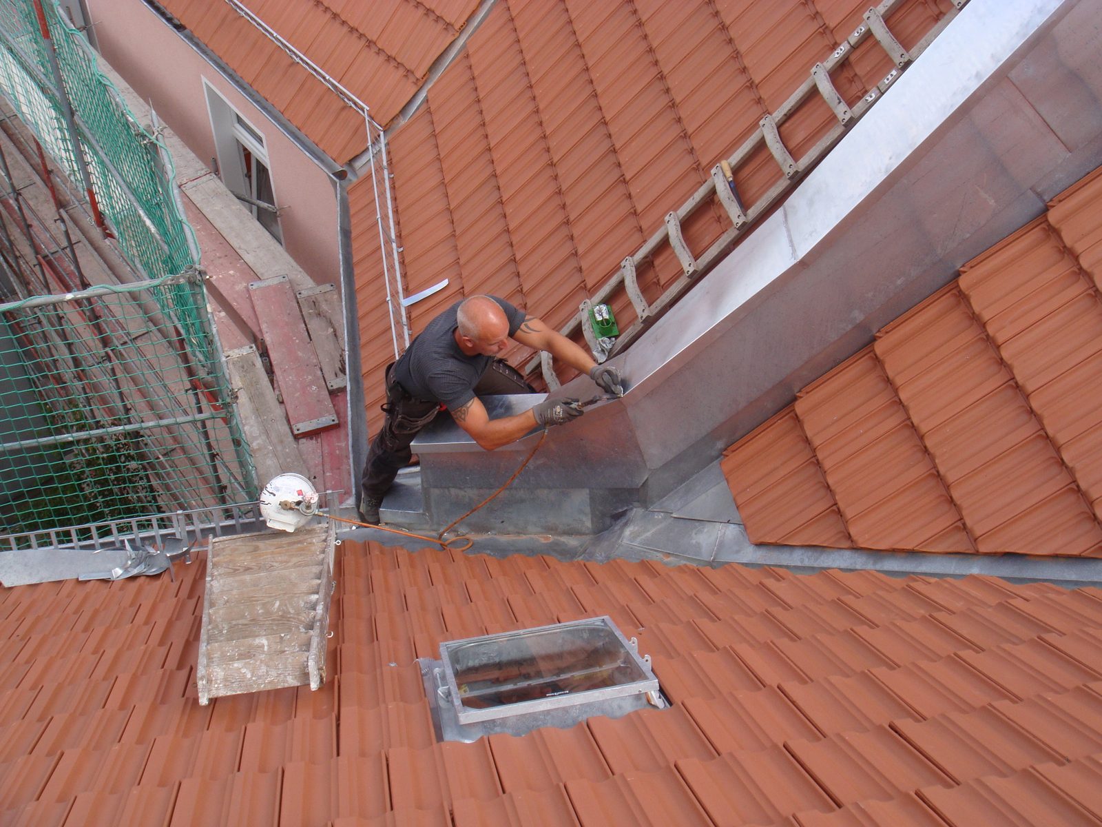 Dachdecker der Betoplan Dachbau bei Klempnerarbeiten an der Kehle eines Berliner Ziegeldachs